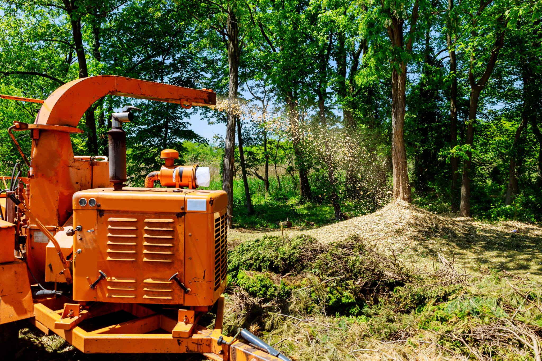 Wood Chipper in Action captures a wood chipper or mulcher shooting chips over a fence
